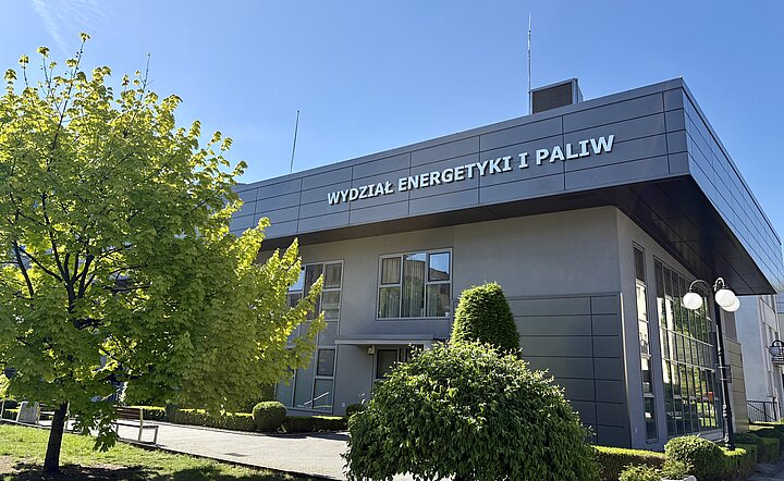 The Faculty of Energy and Fuels building stands modern and bright under a clear blue sky, surrounded by lush greenery.